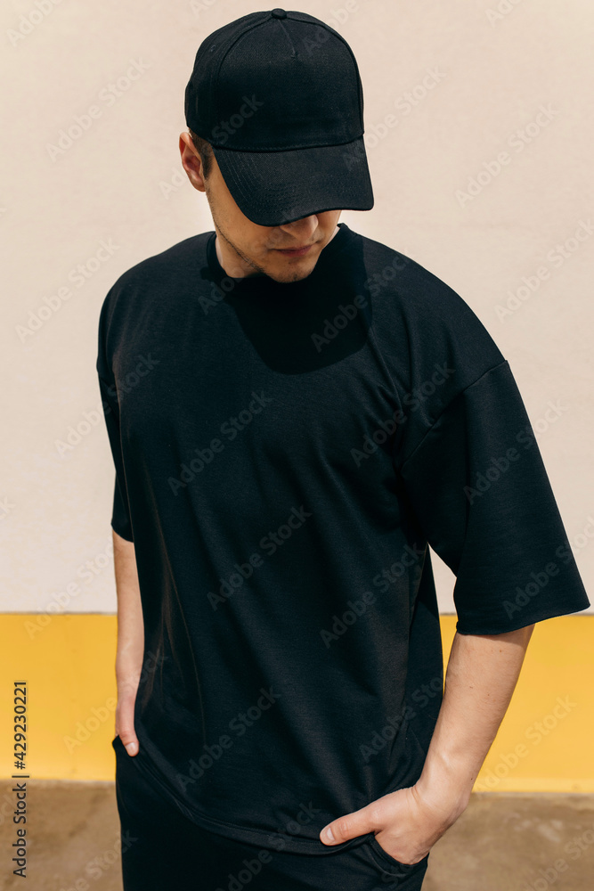 Man wearing black blank t-shirt and a black baseball cap with space for ...