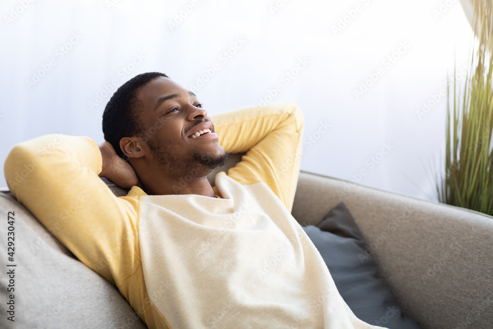 Closeup of black guy relaxing on couch at home - obrazy, fototapety, plakaty 
