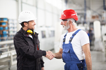 Portrait of workers in factory. Colleagues handshake in factory