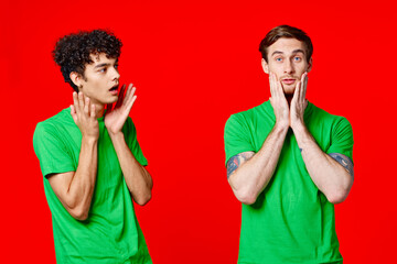 two men holding their heads in green T-shirts on a red background