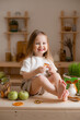 cute little girl eats natural pastille at home in a wooden kitchen. Food for children from natural products