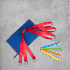 Wall Mural - Red Lanyards with key ring Keychain blue notebook paper pens colors. isolated over grey desk background.