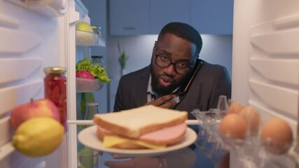 Wall Mural - busy businessman loosening tie, talking on phone and taking plate with sandwich from refrigerator fo
