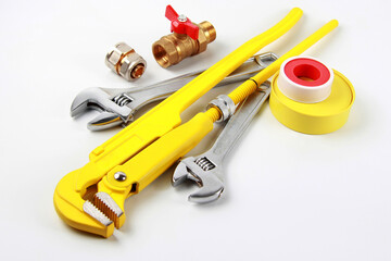 Set of new adjustable steel keys, brass water tap with adapter and sealing tapes on white background. The concept of repair, installation and connection of plumbing or gas installations.