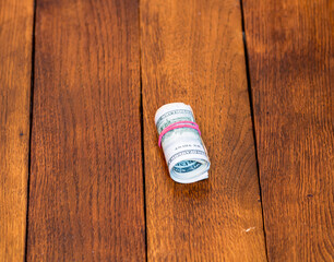 Wall Mural - Closeup of a roll of USD banknotes on a wooden surface