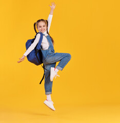 Cheerful schoolgirl with backpack having fin and jumping