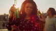 © stockbusters - Afro woman enjoying party with beer outdoors. African girl dancing at party.