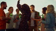 © stockbusters - Multiethnic friends toasting with beer at sunset party. Smiling friends dancing.