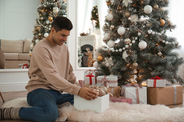 Man decorating Christmas tree in beautiful room interior