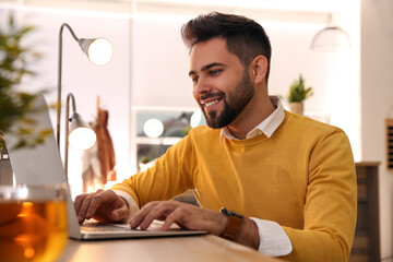 Wall Mural - Man working with laptop at table in cafe