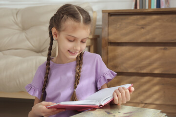 Wall Mural - Cute little girl reading book at home