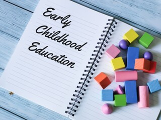 phrase early childhood education written on notebook with a bunch colorful wooden cubes.