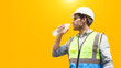 The construction worker drinks water to quench his thirst.