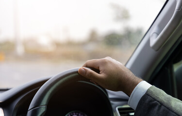 Young man driving car on the road. Car steering wheel handle.