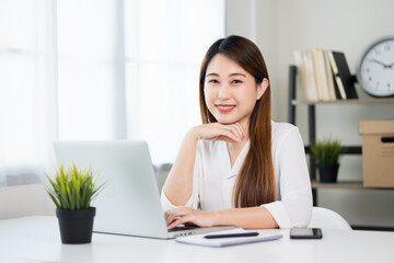 Young asian beautiful business woman working with laptop sitting at home. Smiling charming happy young female doing homework meeting conference with team at home.