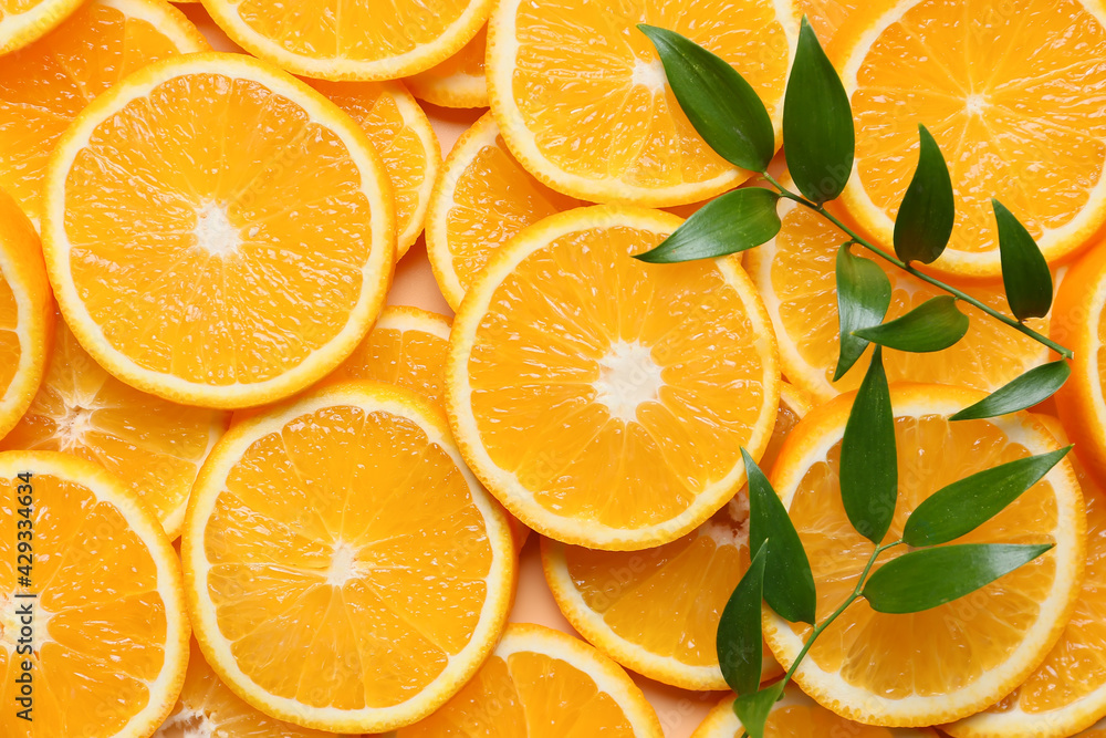 Pieces of fresh oranges with green leaves as background