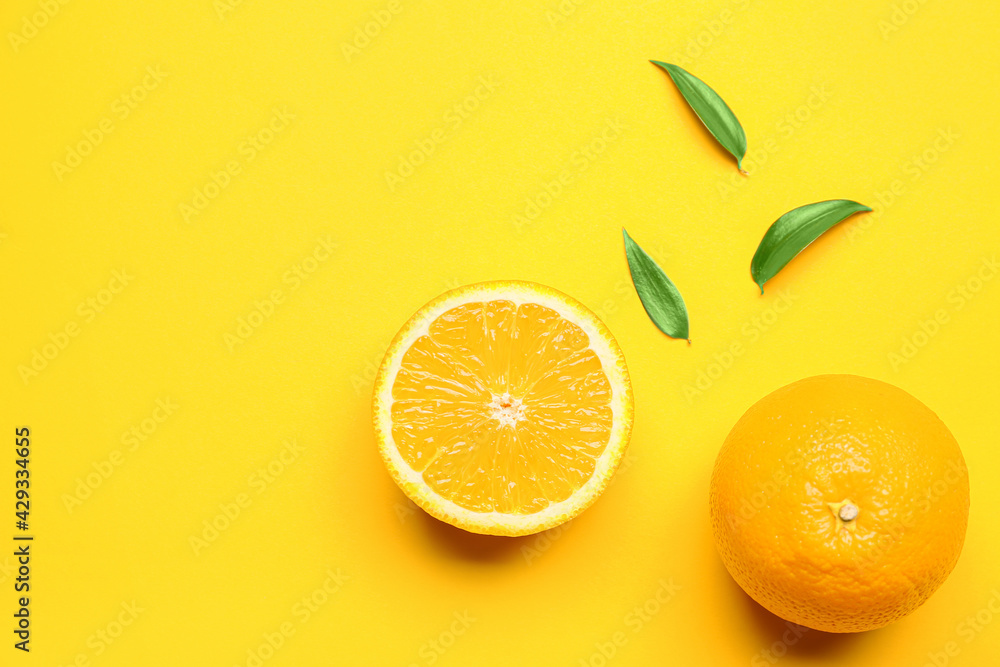 Fresh oranges with green leaves on color background