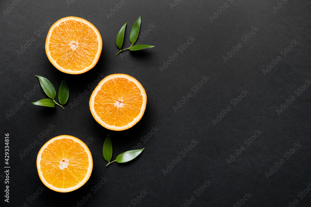Pieces of fresh oranges with green leaves on dark background