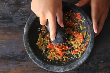 The process of making chili sauce from chilies using manual kitchen utensils, namely mortar.