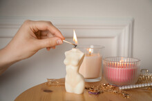 Woman Lighting Female Body Shaped Candle On Wooden Table, Closeup. Stylish Decor