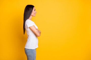 Wall Mural - Photo of pretty adorable young woman dressed white t-shirt arms crossed looking empty space isolated yellow color background