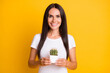 © deagreez - Photo of adorable charming young woman dressed white t-shirt holding green cactus pot isolated yellow color background
