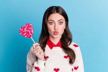 Poster - Photo of funny flirty young woman dressed hearts print pullover holding lollipop sending kiss isolated blue color background