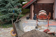 Wheelbarrow, Concrete Mixer And Stack Of Sand In Front Of A Rural House 