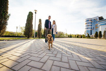 Romantic couple is on a walk in the city with their dog