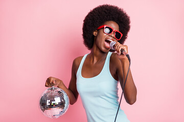 Wall Mural - Photo of young dark skin celebrity girl hold disco ball party sing karaoke isolated on pink color background