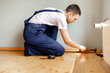 © Ruslan Ivantsov - To make repairs. Installing a new skirting board. a man makes repairs in a room