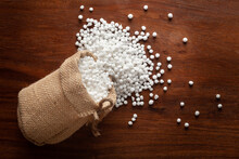Close-up Of Organic White Sago Or Sabudana Big Size Spilled Out From A Laying Jute Bag Over A Wooden Brown Background.