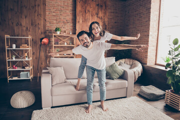 Wall Mural - Full length body size view of attractive cheerful couple having fun piggy backing good mood at loft style interior home house indoor