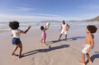 © Wavebreak Media - African american parents and two children having fun playing with ball at the beach
