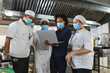 © Wavebreak Media - Diverse group of professinal chefs having meeting with kitchen manager wearing face masks