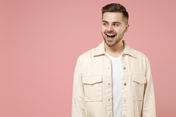 Young smiling happy positive surprised excited fun trendy fashionable caucasian man 20s in jacket white t-shirt look aside isolated on pastel pink background studio portrait. People lifestyle concept.