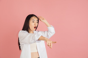 Wall Mural - Asian young woman's portrait on pink studio background. Concept of human emotions, facial expression, youth, sales, ad.