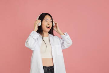 Wall Mural - Asian young woman's portrait on pink studio background. Concept of human emotions, facial expression, youth, sales, ad.