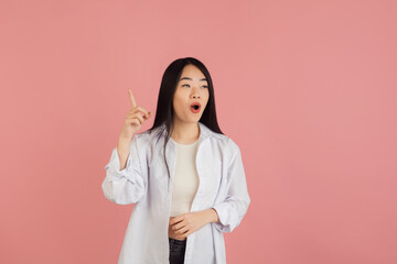 Wall Mural - Asian young woman's portrait on pink studio background. Concept of human emotions, facial expression, youth, sales, ad.