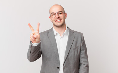 bald businessman smiling and looking friendly, showing number two or second with hand forward, counting down