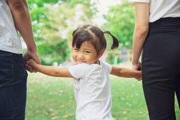 Asian happy little girl holding her parent hand in public park. friendship, safety, support and Asian family concept