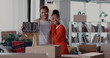 © Fractal Pictures - African young modern family standing together holding sold sign poster celebrating moving house lifestyle event in empty home. Excitement. Relationship.