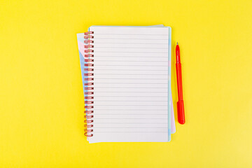 Wall Mural - open spiral notepad on a yellow background with a pen. top view, stack of notepad with blank sheet. school concept, businessman work