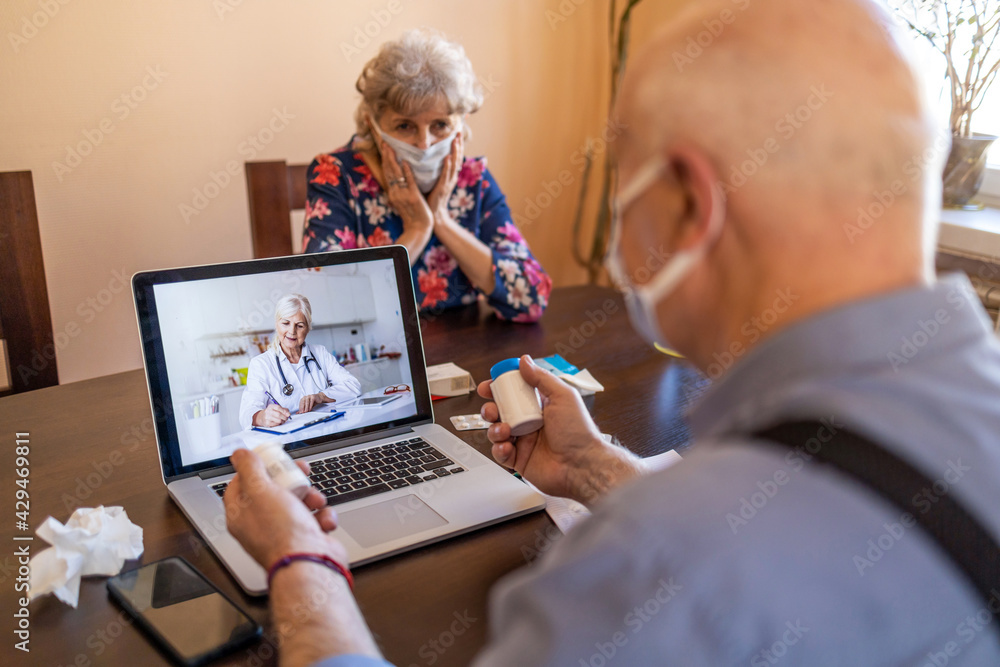 Senior couple consulting with a doctor on laptop at home
 - obrazy, fototapety, plakaty 