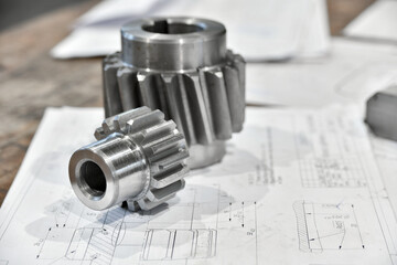 A cogwheel made on a gear cutting machine lies on the technical drawings.