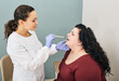 © Peakstock - Throat exam. Doctor using inspection spatula check-up overweight woman's throat
