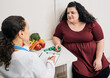 © Peakstock - Nutritionist consultation. Dietitian plans meal plan for a female overweight patient