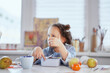 © boytsov - Food is perfect. Kid showing thumbs up gesture. The girl is having dinner from the lunchbox sitting at the table. Small cute schoolgirl having lunch. Tasty eating. High quality image