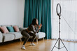 © shevtsovy - Attractive Woman virtual workout at home using smartphone. Fitness workout exercises online women at home. Fitness influencer personal trainer coach recording on smartphone camera new content for