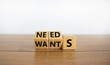 Wants or needs symbol. Turned cubes and changed the word 'wants' to 'needs'. Beautiful wooden table, white background, copy space. Valentines day and wants or needs concept.